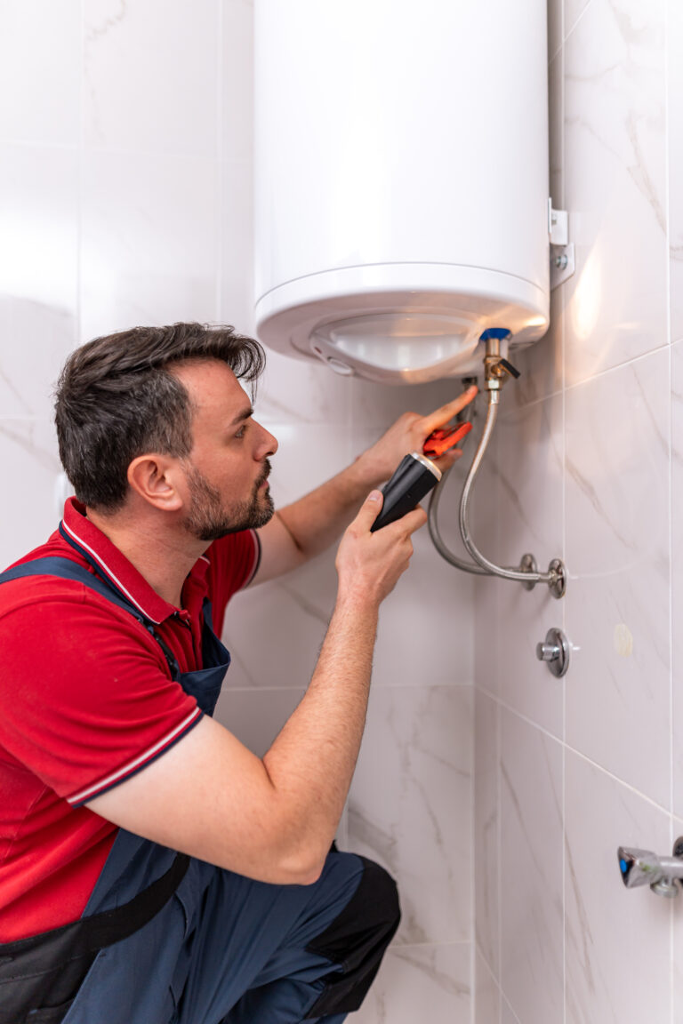 man repairs water heater at home during daylight hours in a well lit bathroom